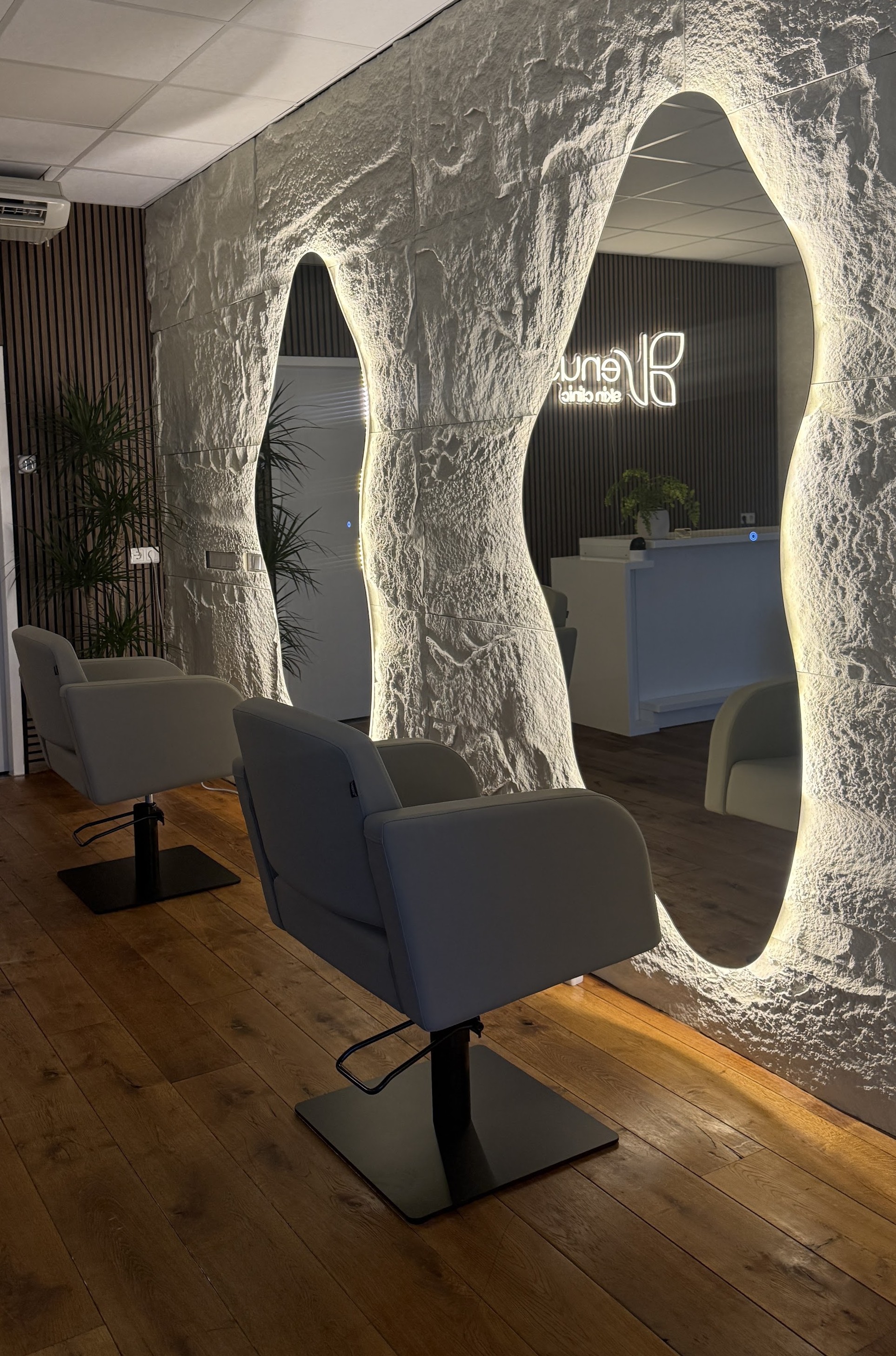 De stenen wand van Venus Skin Clinic met twee verlichte spiegels en een behandelstoel
