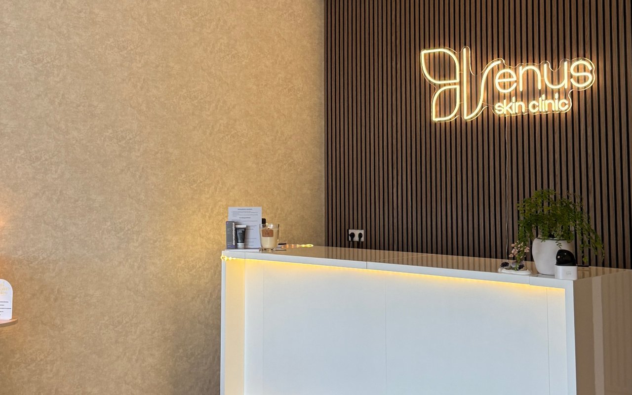 De balie met het verlichte Venus logo op de houten lamellenwand