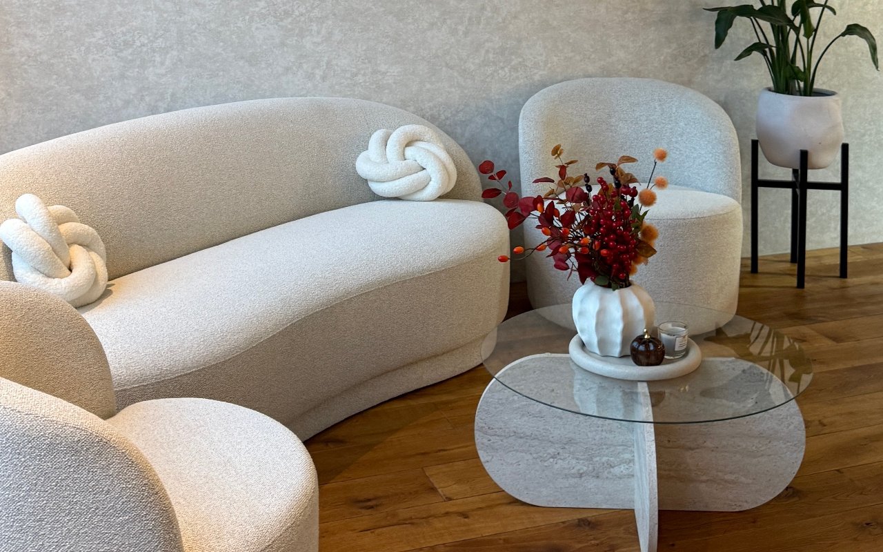 De lounge met crèmekleurige banken, een glazen tafel en bloemen
